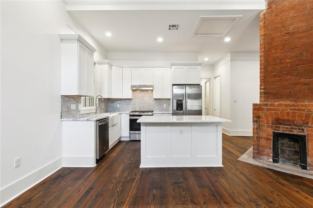 kitchen with a kitchen island, appliances with stainless steel finishes, white cabinets, and backsplash