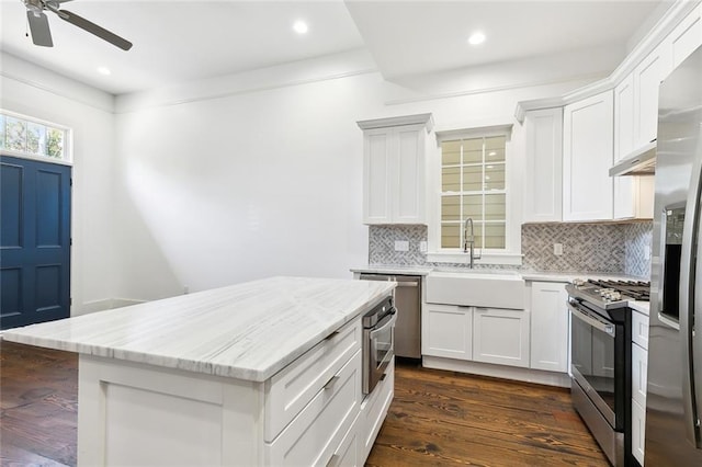 kitchen with sink, white cabinets, dark hardwood / wood-style flooring, light stone counters, and stainless steel appliances