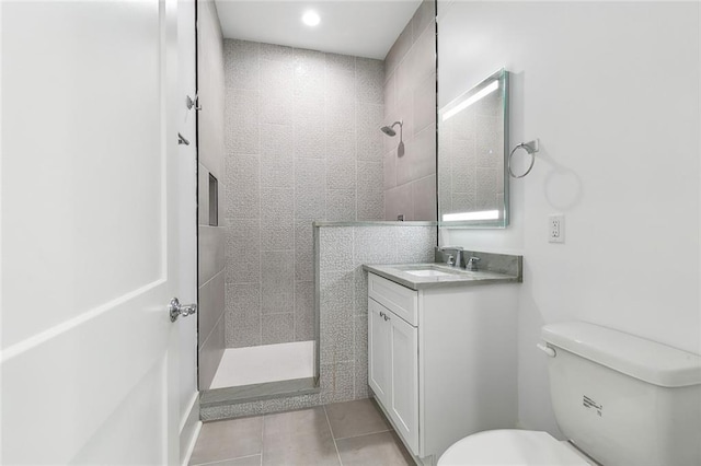 bathroom with vanity, a tile shower, tile patterned floors, and toilet