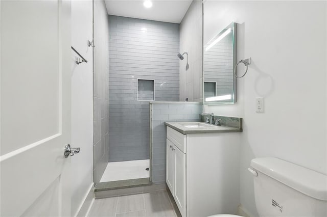 bathroom featuring vanity, toilet, and tiled shower