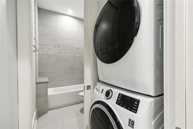 washroom featuring stacked washing maching and dryer and light tile patterned floors