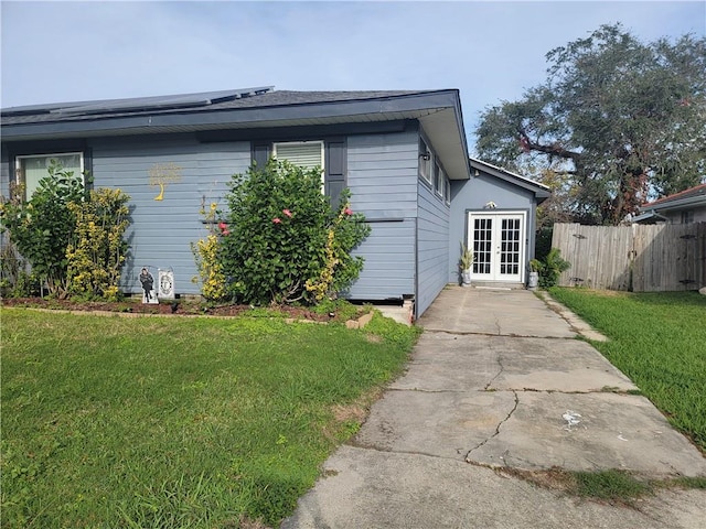 view of property exterior with a lawn and french doors