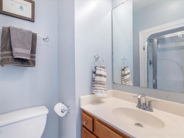 bathroom with a stall shower, vanity, and toilet