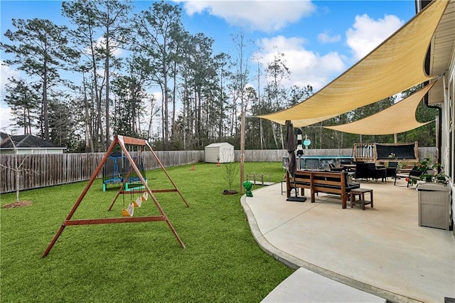 view of playground featuring a lawn, a patio area, and a storage shed