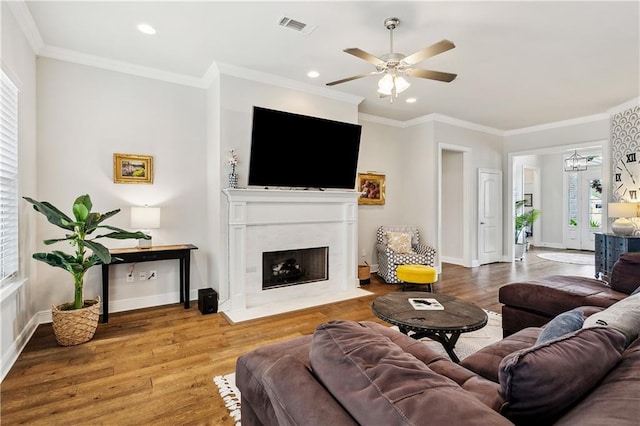 living room with hardwood / wood-style flooring, ceiling fan, and ornamental molding