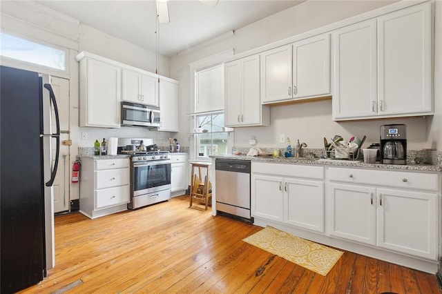 kitchen with white cabinetry, stainless steel appliances, light hardwood / wood-style floors, and a wealth of natural light