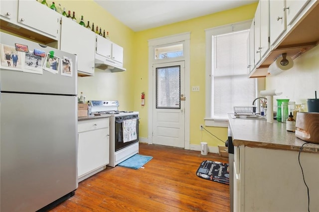 kitchen with sink, white range with gas stovetop, stainless steel refrigerator, hardwood / wood-style floors, and white cabinets