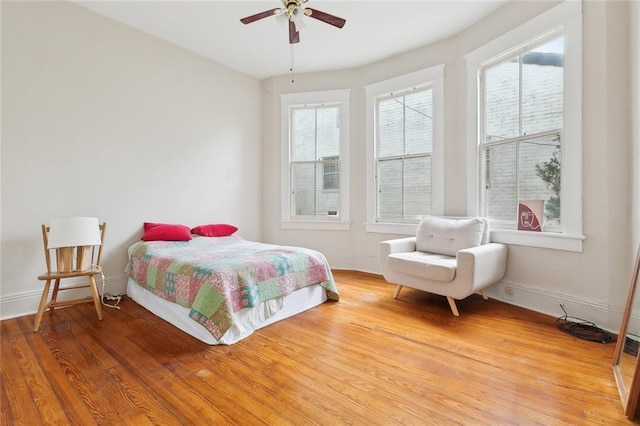 bedroom featuring ceiling fan, hardwood / wood-style floors, and multiple windows