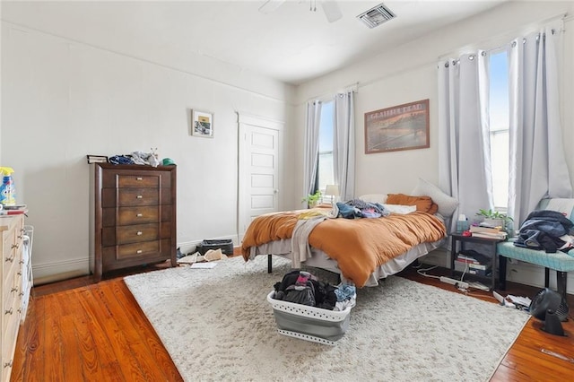 bedroom featuring ceiling fan, wood-type flooring, and multiple windows