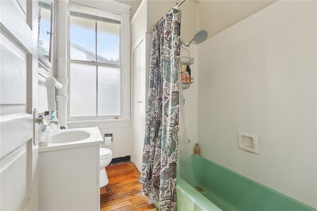 full bathroom with hardwood / wood-style flooring, plenty of natural light, toilet, and shower / bath combo with shower curtain