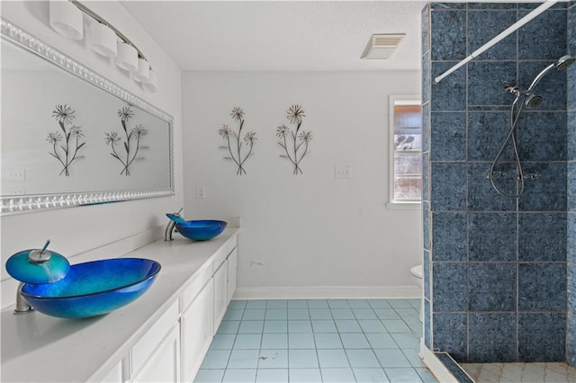 bathroom with vanity, tile patterned flooring, toilet, and tiled shower