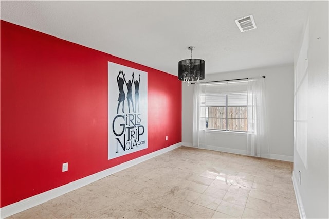 unfurnished room featuring a chandelier