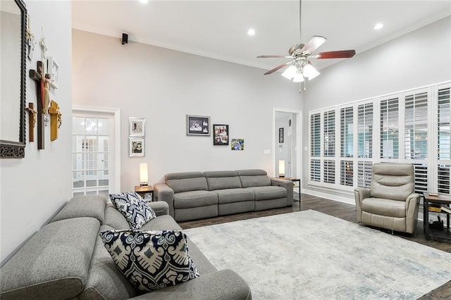 living room with a towering ceiling, ornamental molding, dark hardwood / wood-style floors, and ceiling fan