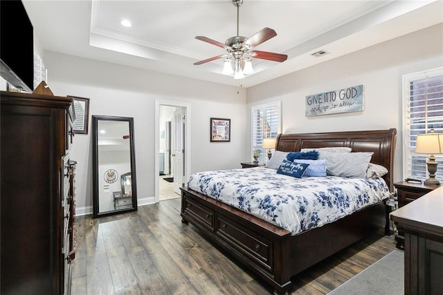 bedroom featuring ensuite bathroom, crown molding, dark hardwood / wood-style floors, a tray ceiling, and ceiling fan