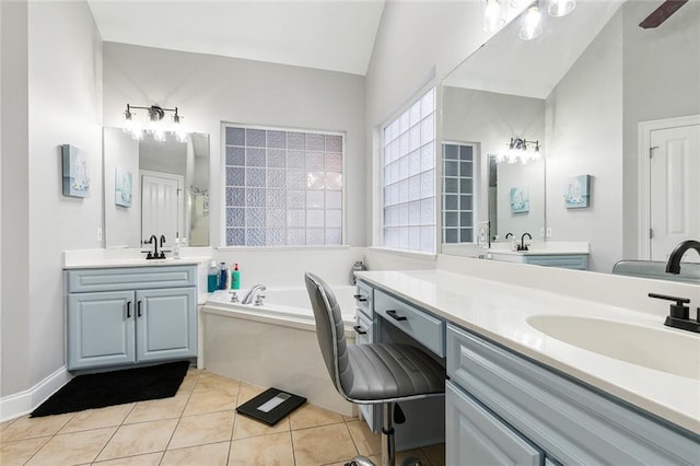 bathroom with tile patterned flooring, vanity, vaulted ceiling, and a tub