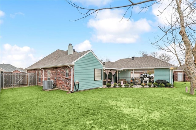 rear view of property with central AC and a lawn