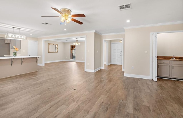 unfurnished living room with crown molding, sink, ceiling fan, and light hardwood / wood-style floors