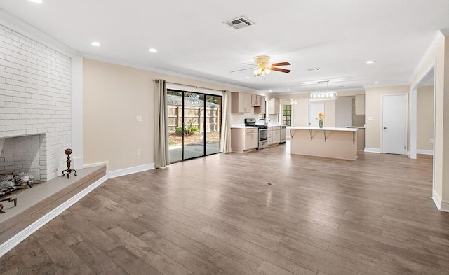 unfurnished living room featuring crown molding, ceiling fan, a fireplace, and light hardwood / wood-style floors