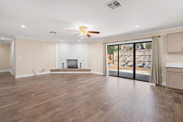 unfurnished living room featuring a brick fireplace, crown molding, hardwood / wood-style floors, and ceiling fan