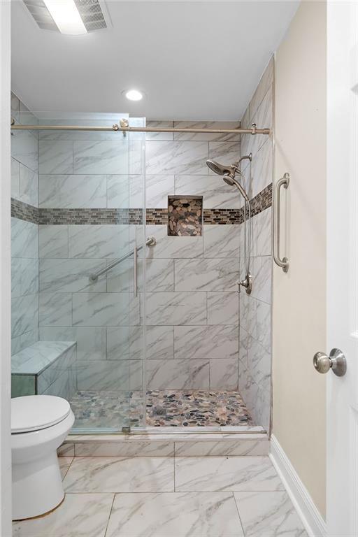 bathroom featuring toilet and a shower with shower door