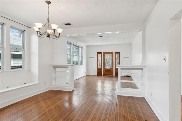 unfurnished dining area featuring dark wood-type flooring and a notable chandelier