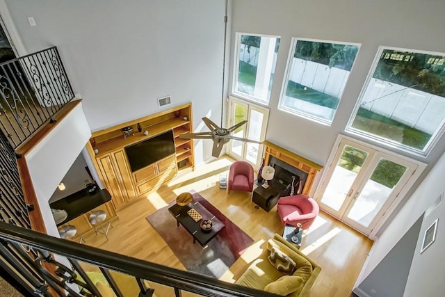 living room with hardwood / wood-style floors, french doors, ceiling fan, and a high ceiling