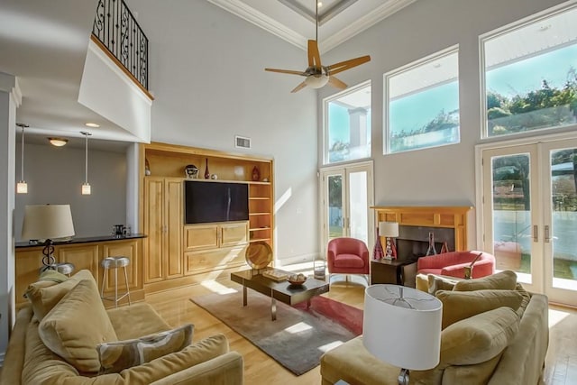 living room featuring french doors, plenty of natural light, crown molding, and light hardwood / wood-style floors