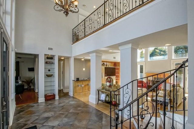 foyer with an inviting chandelier, a high ceiling, and ornate columns