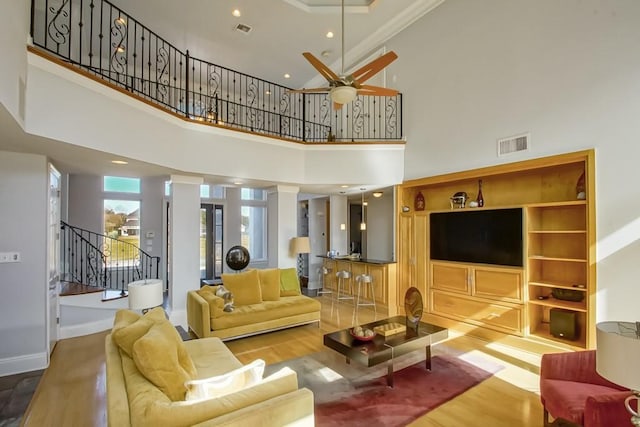 living room featuring ceiling fan, wood-type flooring, and a towering ceiling