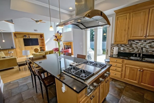 kitchen with sink, a breakfast bar area, island range hood, decorative backsplash, and stainless steel gas stovetop