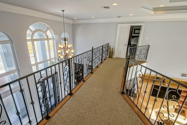 hallway with ornamental molding, carpet floors, and a notable chandelier