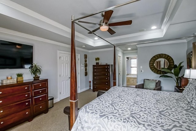 carpeted bedroom featuring crown molding, ensuite bath, a raised ceiling, and ceiling fan