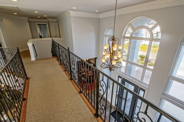 corridor featuring a notable chandelier, carpet floors, ornamental molding, and a high ceiling