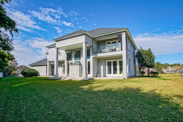 rear view of property featuring a balcony, a yard, and french doors