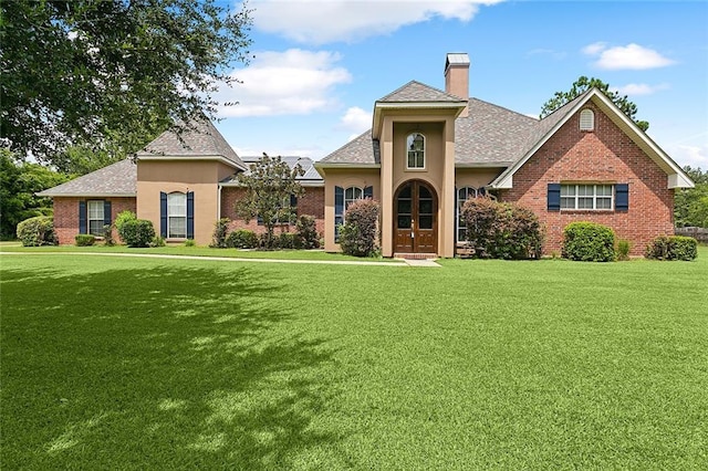 view of front facade featuring a front yard, brick siding, and a chimney