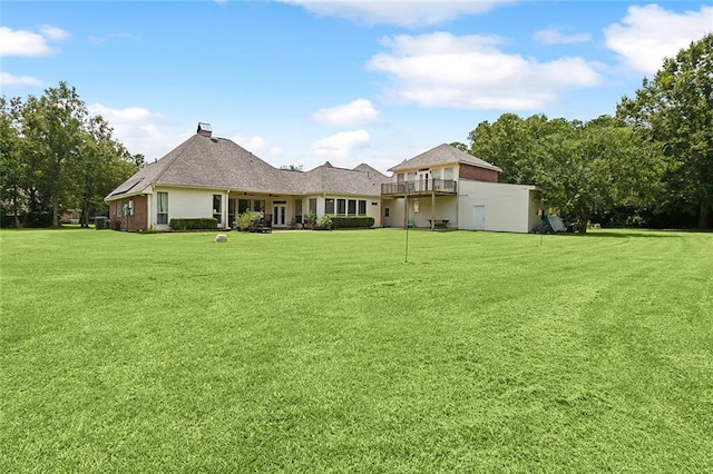 back of house featuring a balcony and a yard