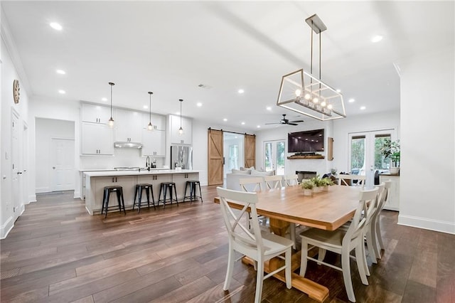 dining room featuring french doors, sink, dark hardwood / wood-style flooring, ceiling fan, and a barn door