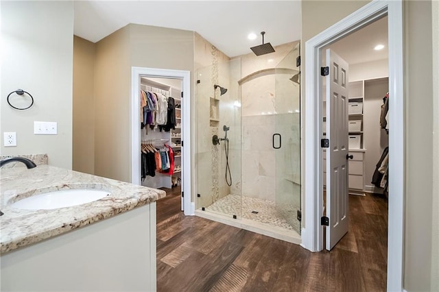 bathroom with wood-type flooring, a shower with door, and vanity