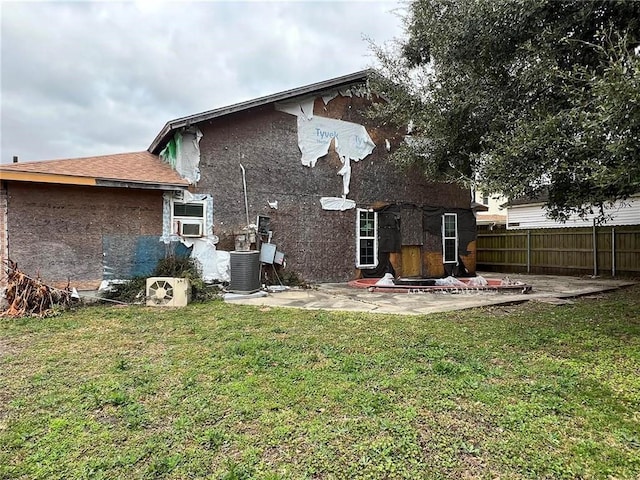 rear view of property with central AC unit, a patio area, and a lawn