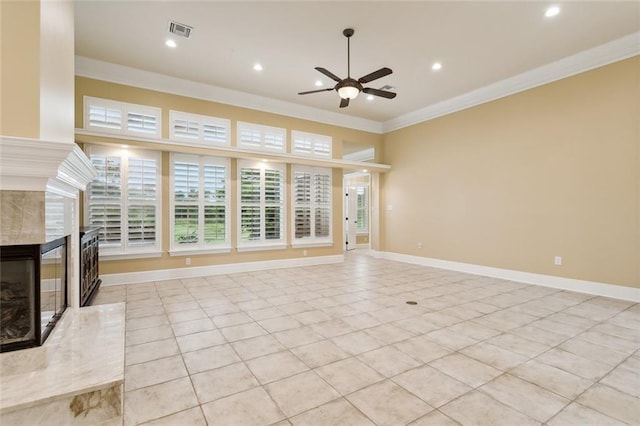 unfurnished living room featuring crown molding, light tile patterned floors, ceiling fan, and a fireplace