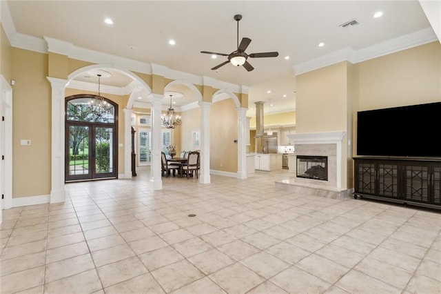 unfurnished living room featuring light tile patterned floors, crown molding, ceiling fan with notable chandelier, and decorative columns