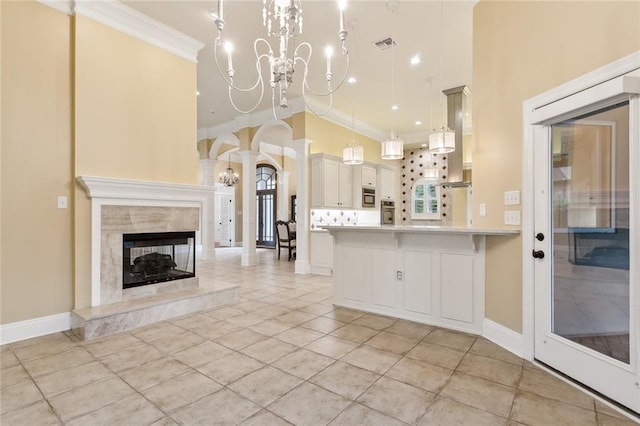 kitchen featuring crown molding, white cabinetry, a notable chandelier, decorative light fixtures, and kitchen peninsula