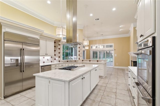 kitchen featuring stainless steel appliances, ornamental molding, a kitchen island, and pendant lighting