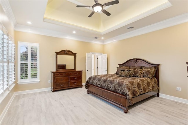 bedroom featuring crown molding, a raised ceiling, and light wood-type flooring