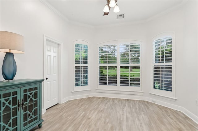 unfurnished dining area featuring ceiling fan, ornamental molding, and light wood-type flooring