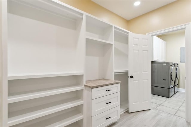 walk in closet featuring electric panel, independent washer and dryer, and light hardwood / wood-style floors