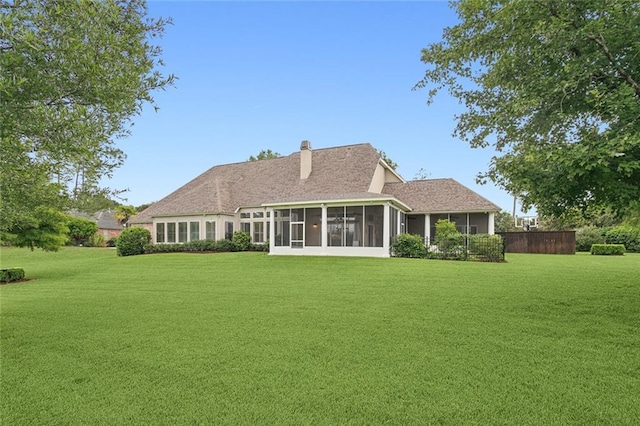 rear view of house with a yard and a sunroom