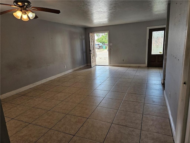 empty room featuring ceiling fan, a textured ceiling, and light tile patterned flooring