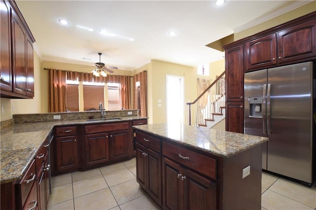 kitchen with sink, stainless steel fridge, light stone counters, a kitchen island, and kitchen peninsula