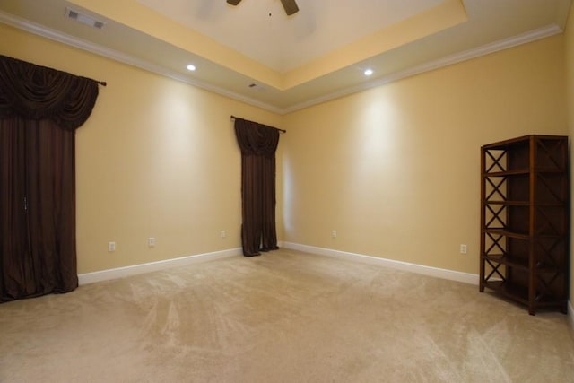 carpeted spare room with a tray ceiling, ornamental molding, and ceiling fan